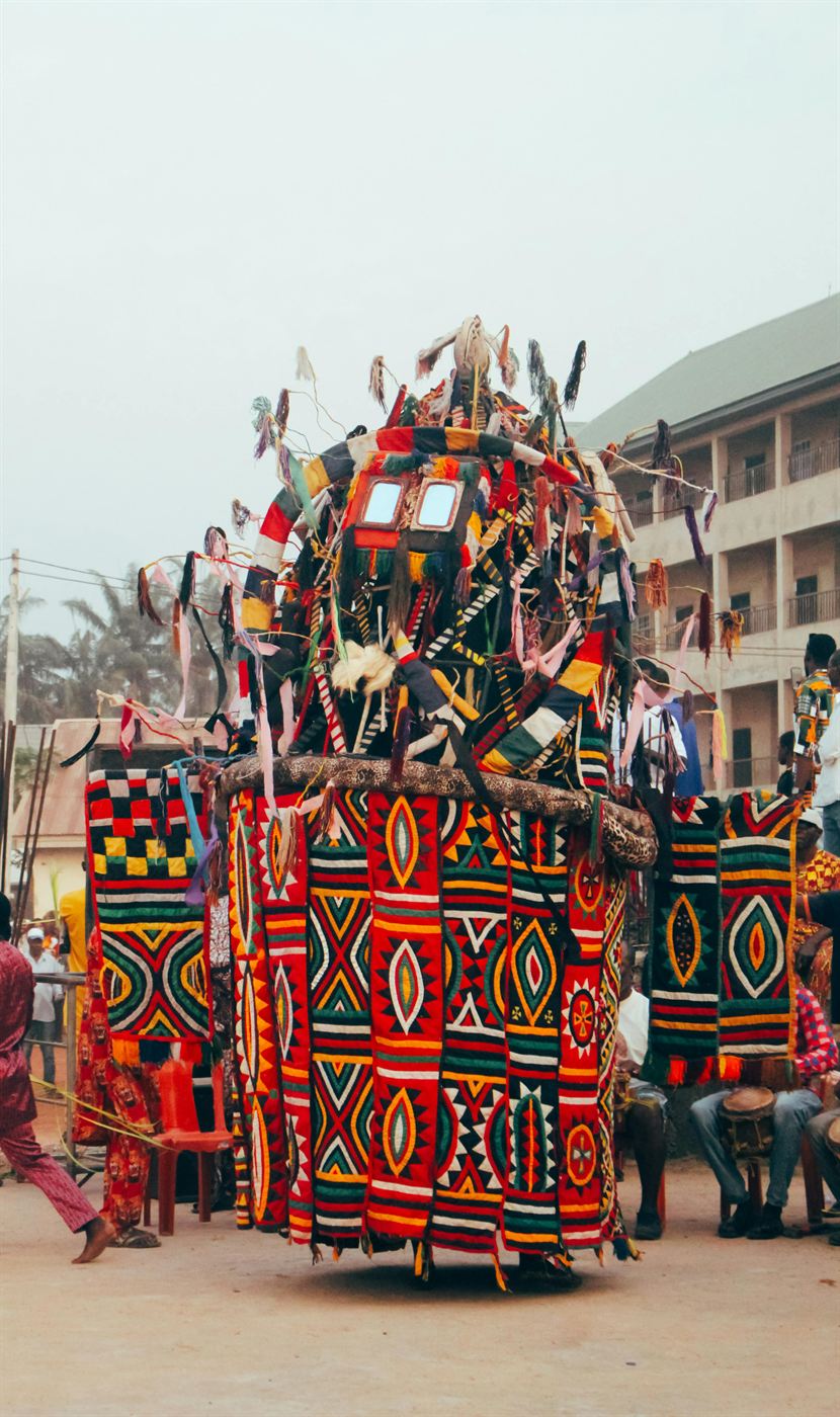 An Egungun masquerade in vivid layered textiles during a Yoruba celebration