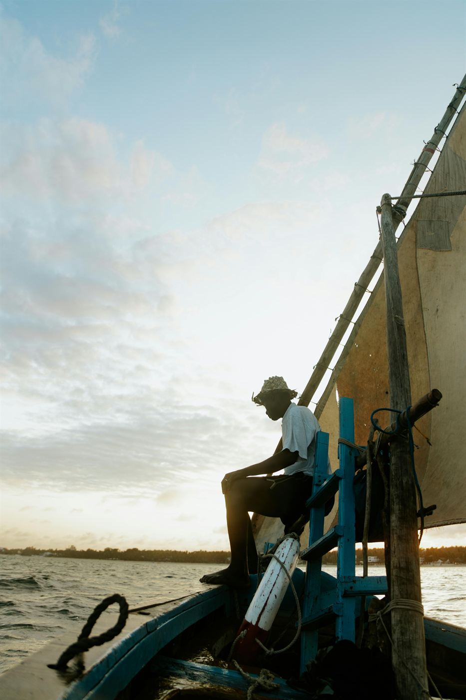 A boatman on a traditional dhow at dusk on the Kenyan coast